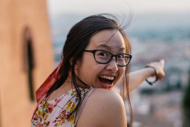 a student sitting atop a building in Granada excitedly pointing into the distance